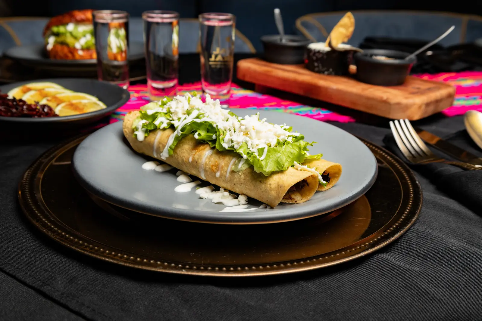 Flautas con crema y queso sobre mantel negro