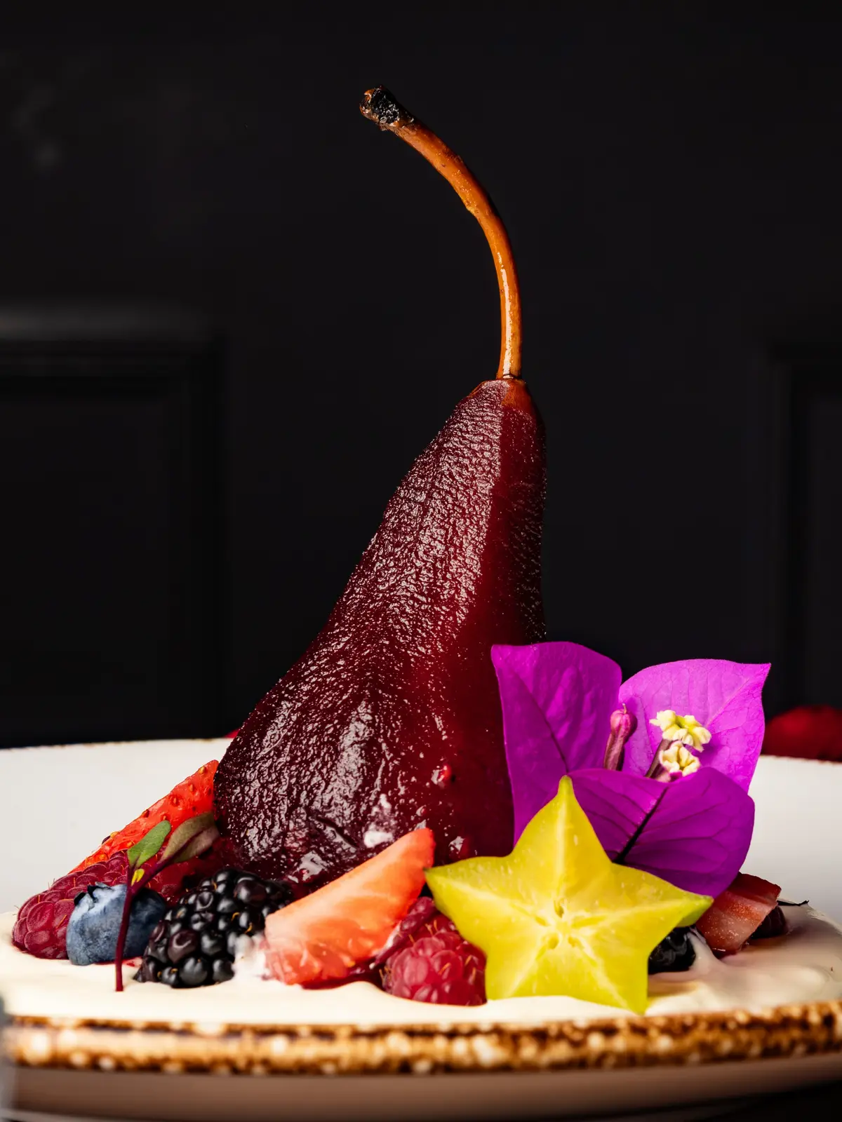 Pera al vino con frutos rojos, carambola y flor de buganvilia