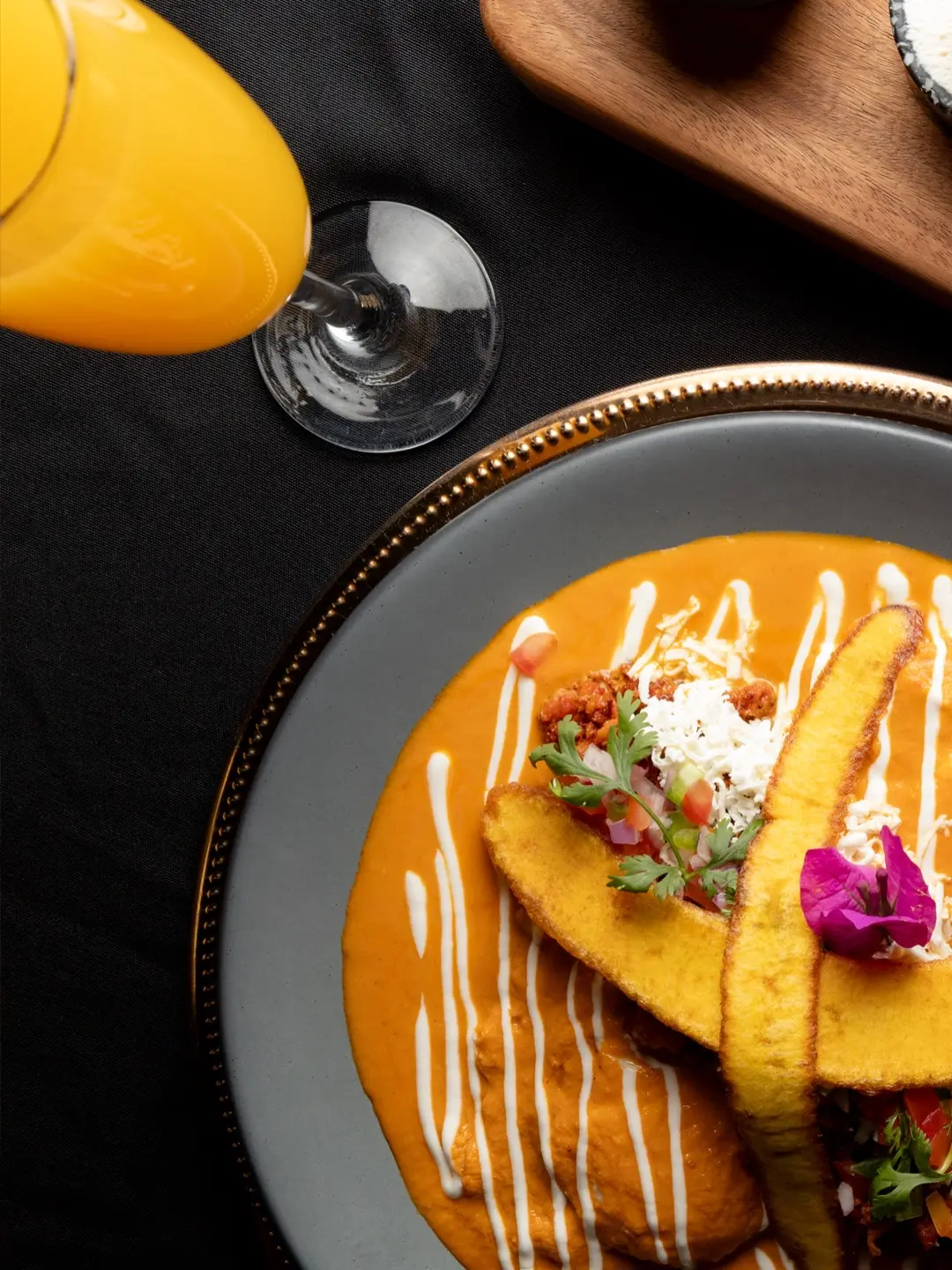 Platillo con salsa naranja, plátano y flores, junto a una mimosa