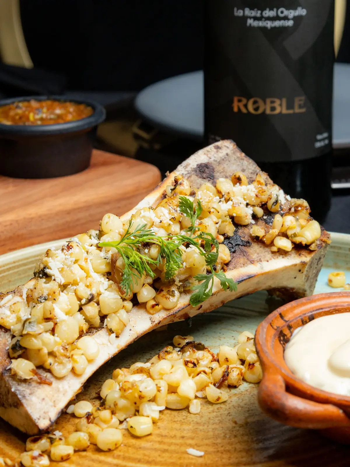 Tuétano con esquites junto a una botella de vino